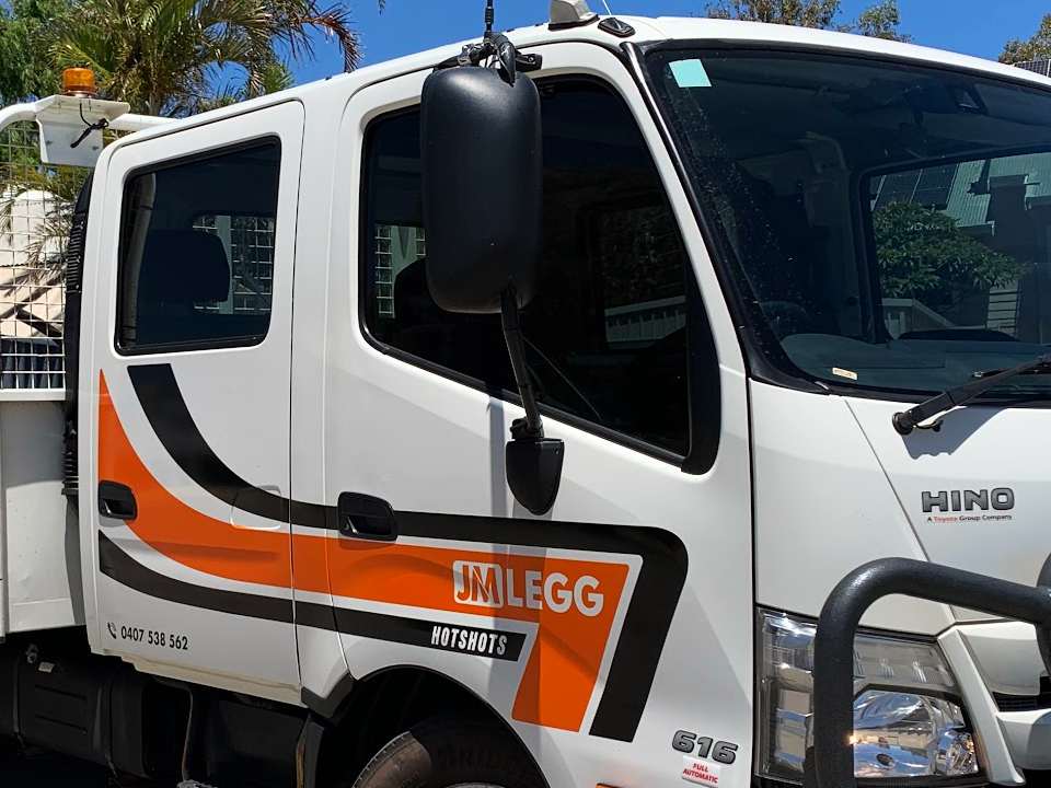 The JM Legg Hotshots Hino crew cab and driver's door with the orange and black livery and the door badge